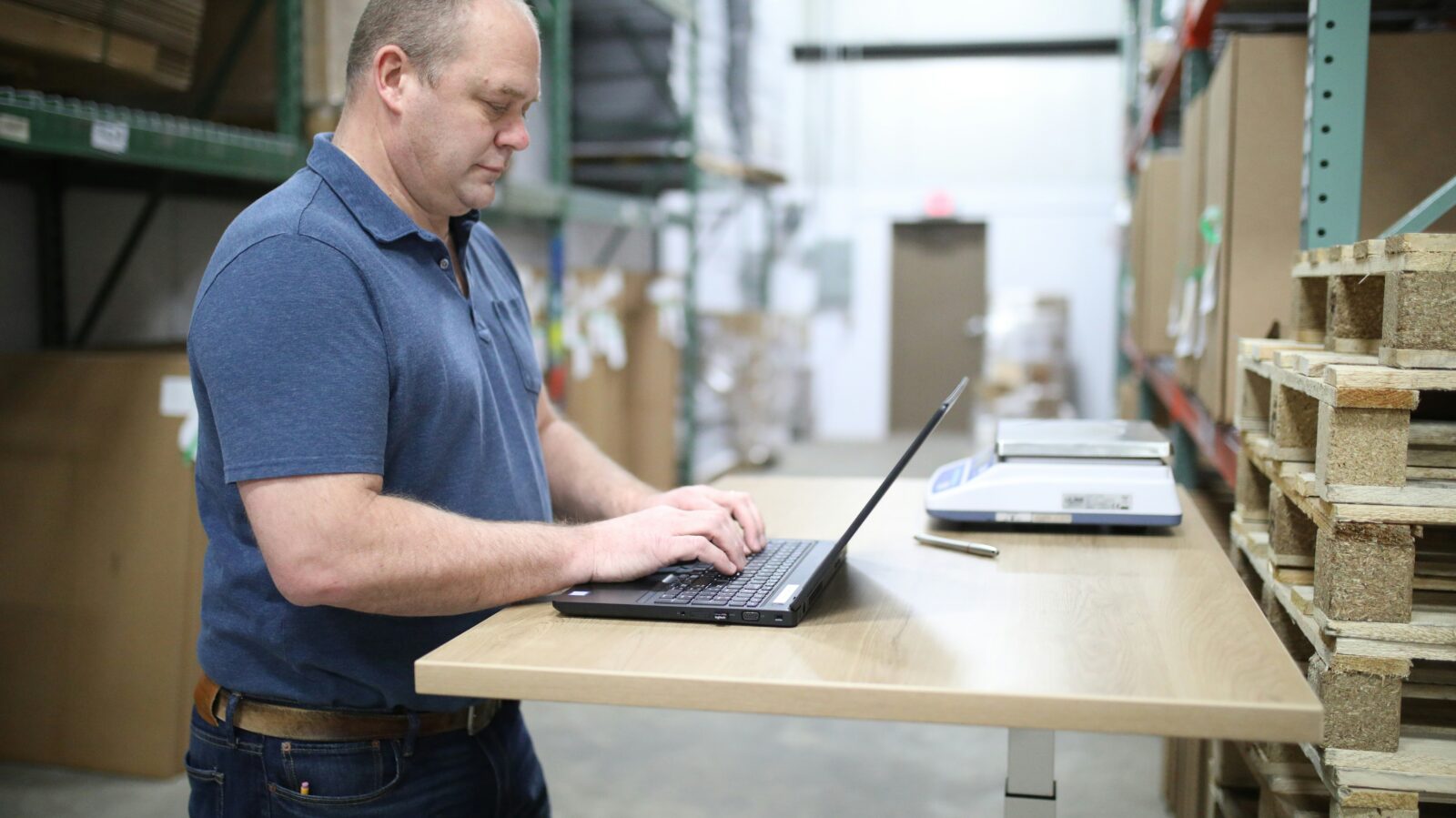 Man working on computer in warehouse, managing 3PL fulfillment operations and e-commerce inventory tracking